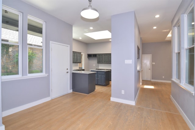 kitchen with decorative light fixtures, light hardwood / wood-style flooring, a skylight, and tasteful backsplash