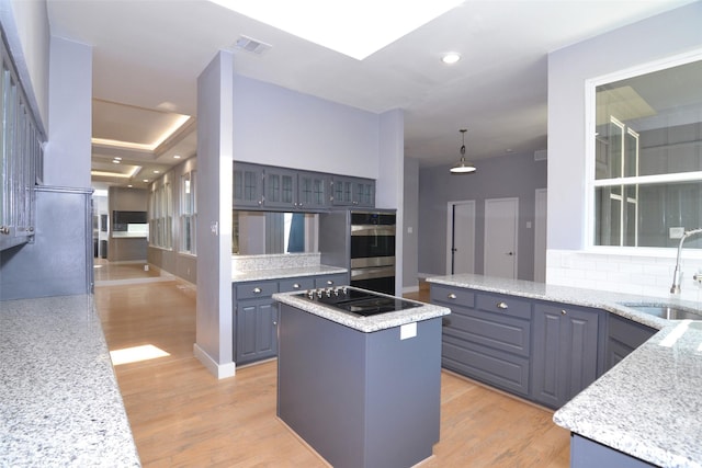 kitchen featuring a center island, black electric stovetop, hanging light fixtures, sink, and backsplash