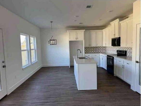 kitchen with white cabinetry, sink, electric range, and a kitchen island with sink