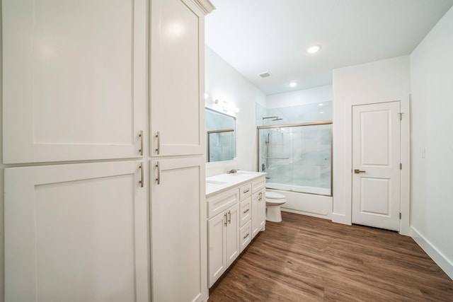 full bathroom featuring enclosed tub / shower combo, hardwood / wood-style floors, vanity, and toilet