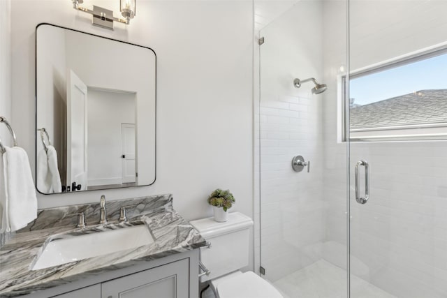 bathroom with toilet, a shower with shower door, and vanity