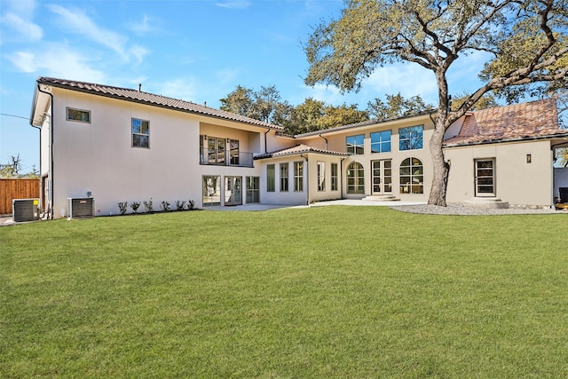 rear view of property with a balcony, a lawn, and central AC