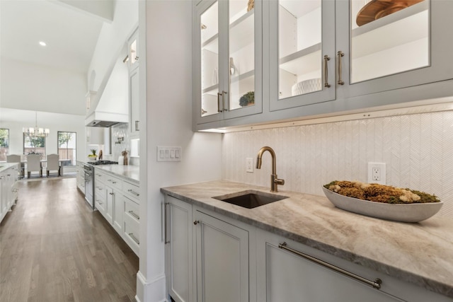 kitchen with sink, white cabinetry, light stone countertops, decorative backsplash, and high end range