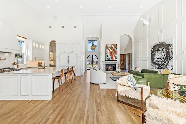 living room featuring sink, light wood-type flooring, and a high ceiling