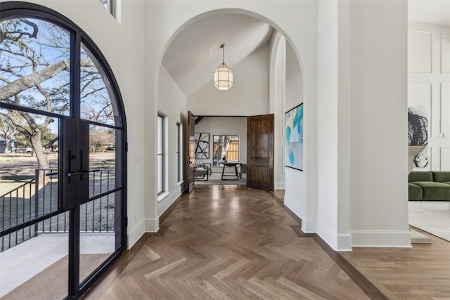 foyer featuring french doors, high vaulted ceiling, and parquet flooring