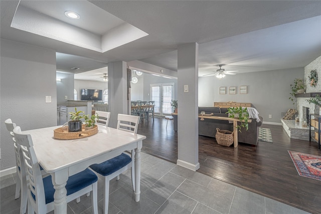 tiled dining space with a fireplace and ceiling fan