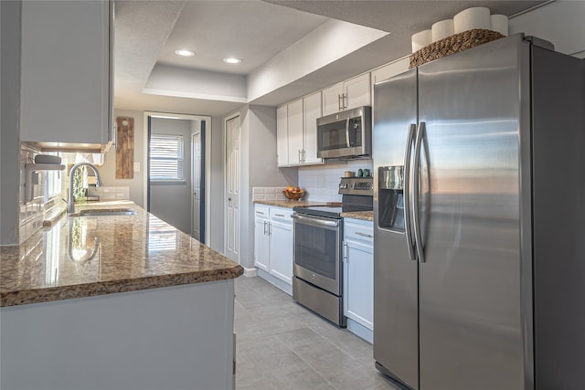 kitchen with sink, white cabinets, a raised ceiling, and appliances with stainless steel finishes