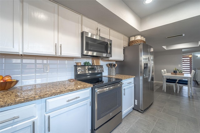 kitchen featuring white cabinets, appliances with stainless steel finishes, dark stone counters, tasteful backsplash, and light tile patterned flooring