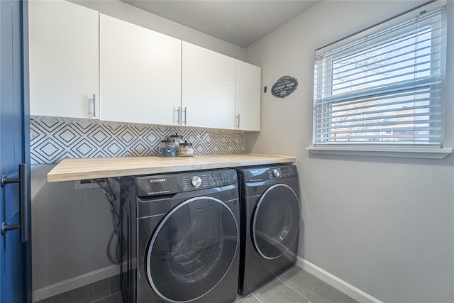 laundry room featuring washing machine and dryer, light tile patterned floors, and cabinets