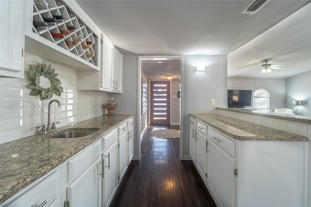 kitchen with white cabinetry, sink, backsplash, dark hardwood / wood-style floors, and stone countertops