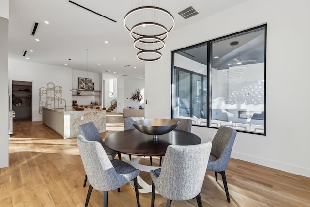 dining area featuring sink, a notable chandelier, and light hardwood / wood-style flooring