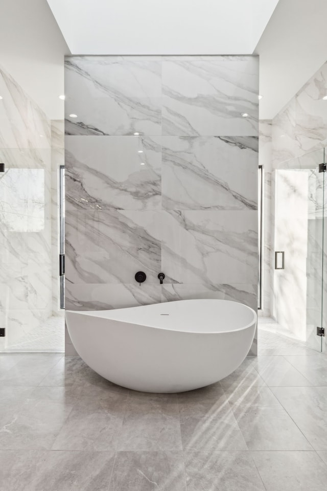 bathroom featuring plus walk in shower and tile walls