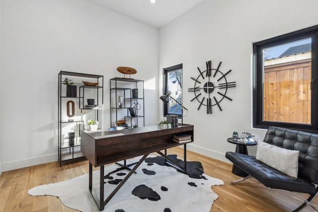 office space featuring hardwood / wood-style flooring and a towering ceiling