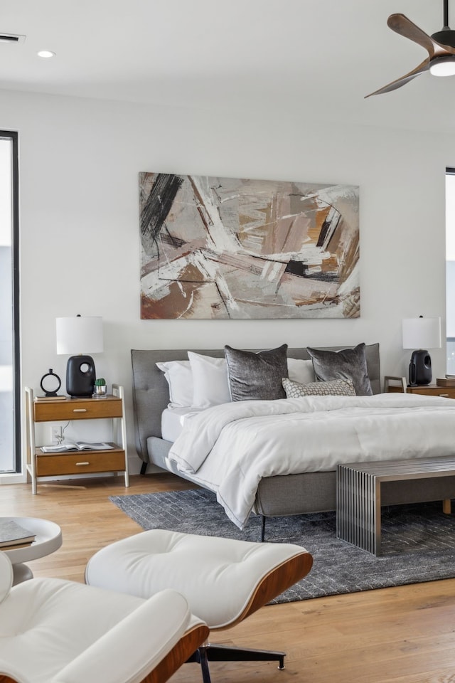 bedroom with multiple windows, wood-type flooring, and ceiling fan