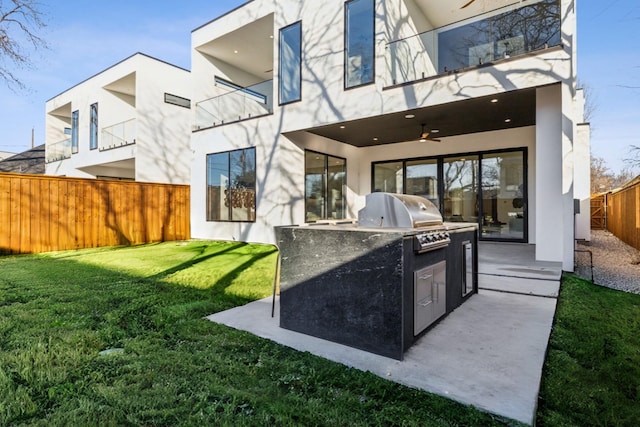 back of house with an outdoor kitchen, a patio area, ceiling fan, and a lawn