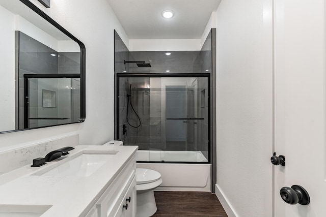 full bathroom featuring toilet, wood-type flooring, shower / bath combination with glass door, and vanity