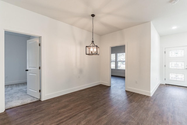 unfurnished dining area with an inviting chandelier and dark hardwood / wood-style flooring