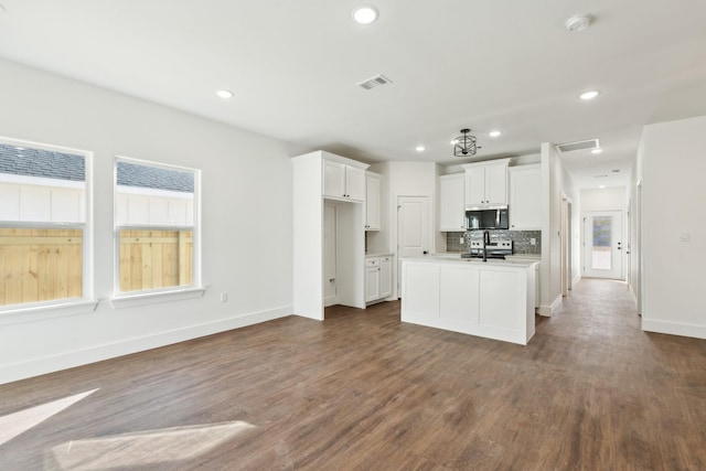 kitchen featuring a kitchen island with sink, decorative backsplash, dark hardwood / wood-style flooring, and white cabinets