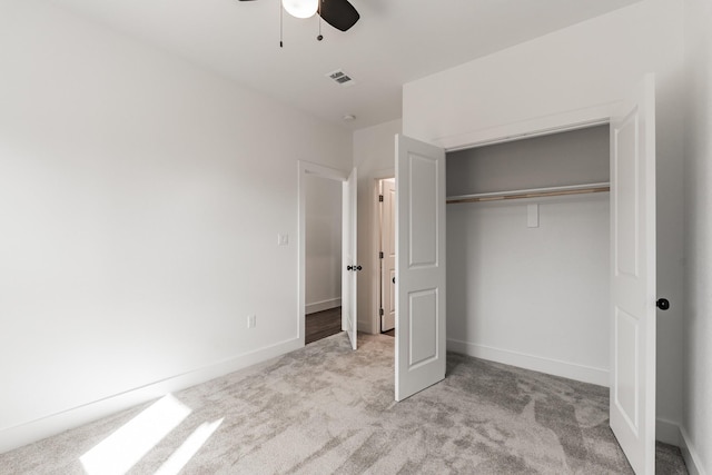 unfurnished bedroom featuring light colored carpet, a closet, and ceiling fan