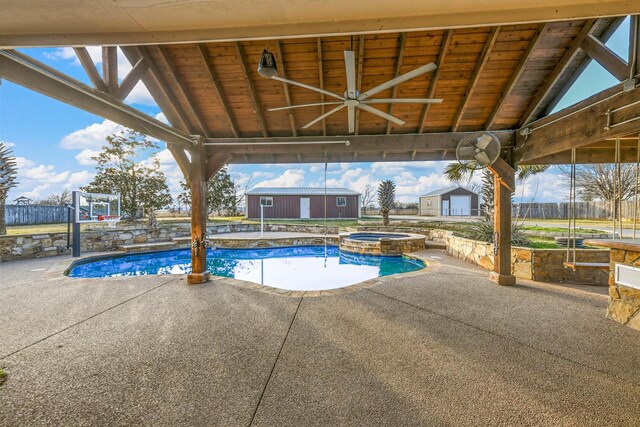 view of swimming pool featuring an in ground hot tub, a patio, and a shed