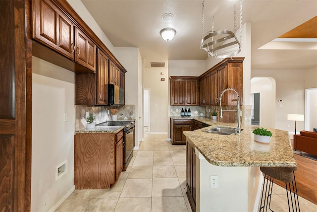 kitchen featuring light stone counters, electric range, light tile patterned floors, sink, and kitchen peninsula