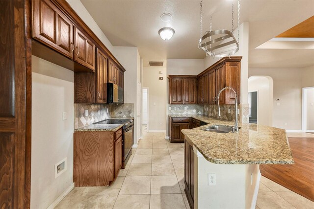 kitchen featuring kitchen peninsula, sink, light stone counters, light tile patterned floors, and black / electric stove