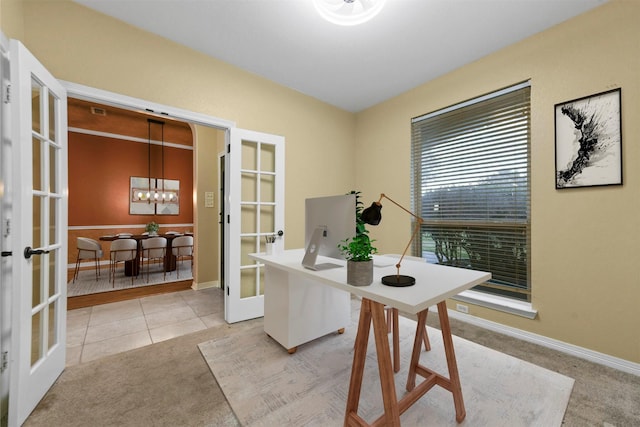 carpeted office with french doors and a chandelier