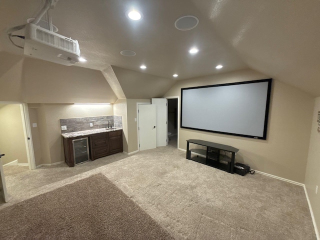 carpeted cinema room featuring bar area and lofted ceiling