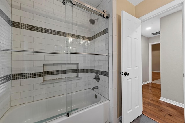 bathroom featuring hardwood / wood-style flooring and shower / bath combination with glass door