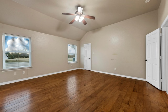 unfurnished room featuring plenty of natural light, dark wood-type flooring, and vaulted ceiling