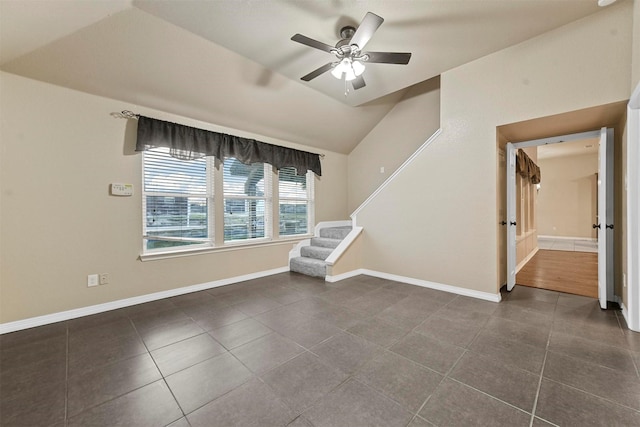 unfurnished room with ceiling fan, lofted ceiling, and dark tile patterned flooring