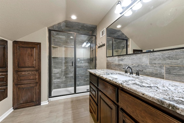 bathroom with lofted ceiling, a shower with shower door, vanity, and backsplash