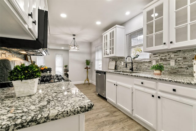 kitchen with hanging light fixtures, appliances with stainless steel finishes, sink, white cabinetry, and light stone countertops