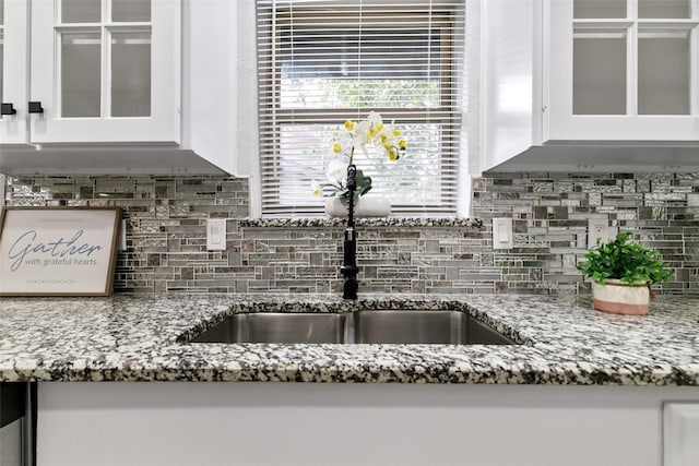 room details with sink, white cabinets, tasteful backsplash, and light stone countertops