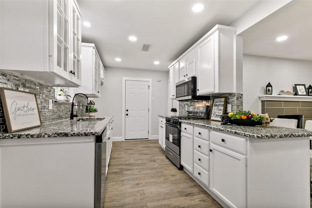 kitchen with sink, light stone counters, white cabinets, and stainless steel appliances