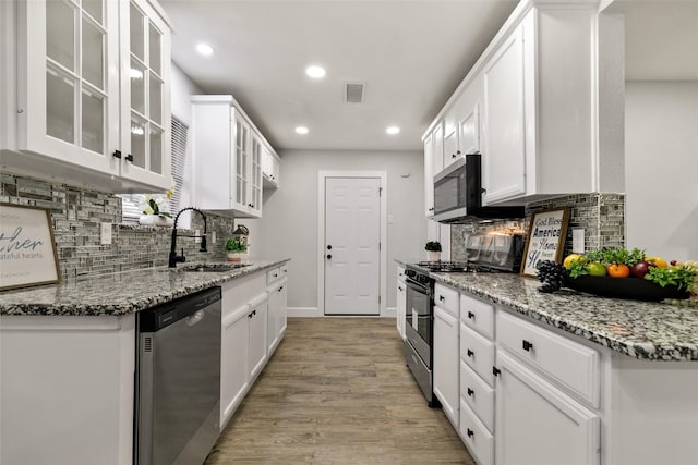 kitchen featuring appliances with stainless steel finishes, sink, white cabinets, light stone countertops, and decorative backsplash