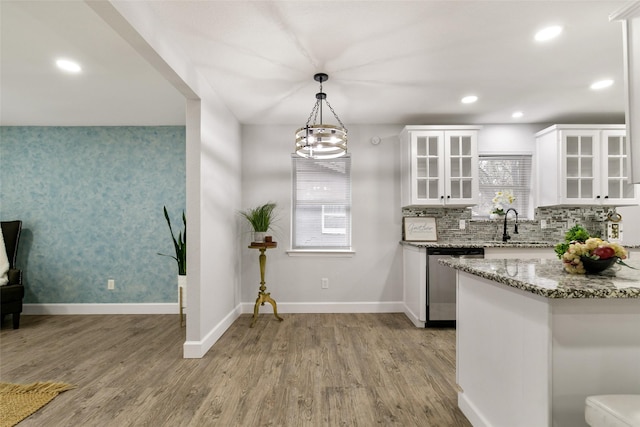 kitchen featuring pendant lighting, white cabinetry, light stone counters, stainless steel dishwasher, and light hardwood / wood-style flooring