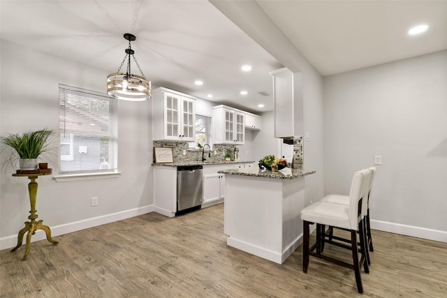 kitchen featuring dishwasher, white cabinetry, hanging light fixtures, light wood-type flooring, and light stone counters