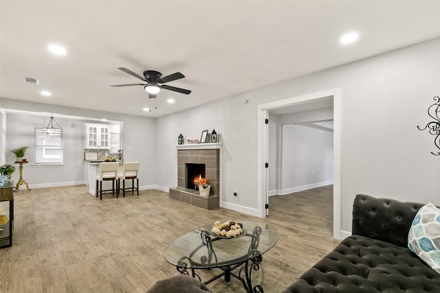 living room with a tiled fireplace, hardwood / wood-style floors, and ceiling fan