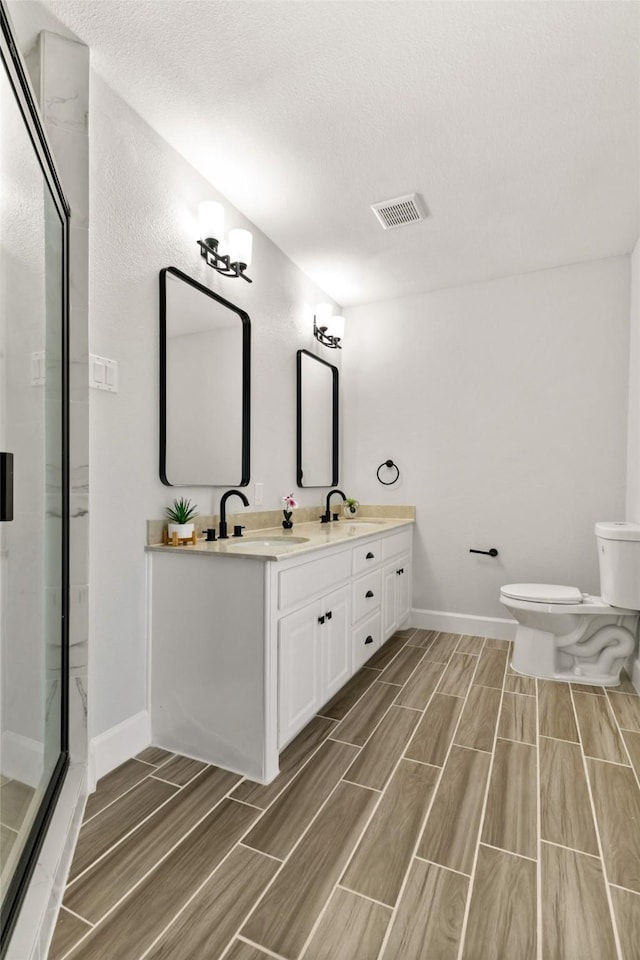 bathroom with vanity, toilet, and a shower with shower door