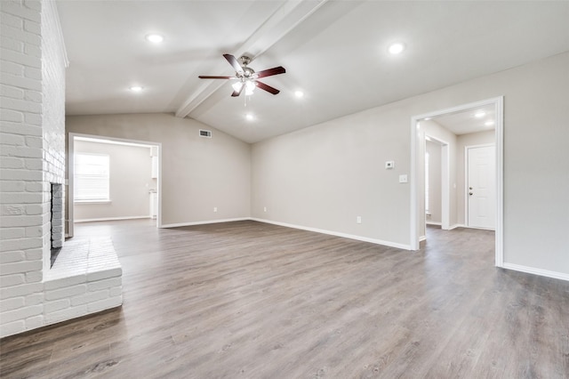 unfurnished living room with a fireplace, wood-type flooring, vaulted ceiling with beams, and ceiling fan