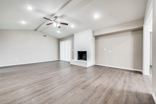 unfurnished living room with ceiling fan, hardwood / wood-style flooring, vaulted ceiling with beams, and a brick fireplace