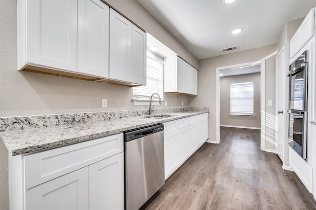 kitchen featuring appliances with stainless steel finishes, sink, plenty of natural light, white cabinetry, and light stone countertops