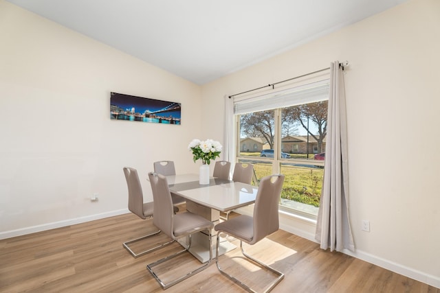 dining area with vaulted ceiling, plenty of natural light, and light hardwood / wood-style floors