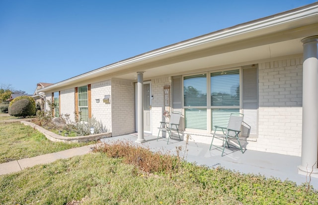 doorway to property featuring covered porch and a lawn