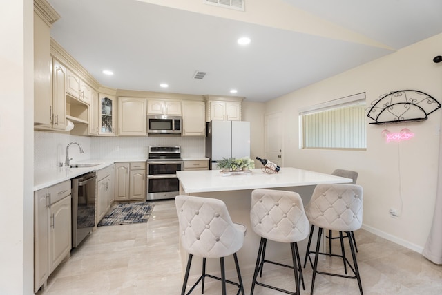 kitchen featuring a kitchen bar, sink, tasteful backsplash, appliances with stainless steel finishes, and a kitchen island