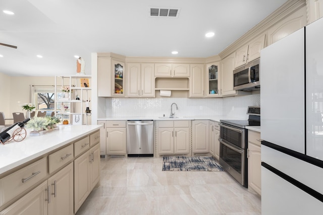 kitchen featuring cream cabinets, stainless steel appliances, sink, and backsplash