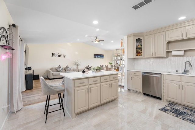 kitchen featuring sink, cream cabinets, decorative backsplash, vaulted ceiling, and stainless steel dishwasher