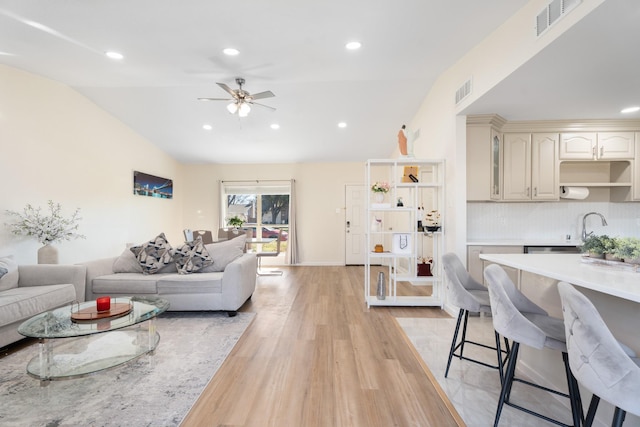 living room featuring ceiling fan, lofted ceiling, and light wood-type flooring