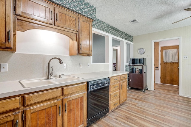 kitchen featuring light hardwood / wood-style floors, sink, a textured ceiling, and black dishwasher